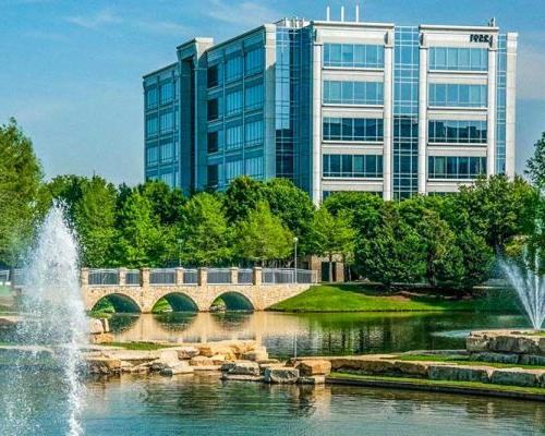 Exterior photo of Dallas office building with fountain and bridge